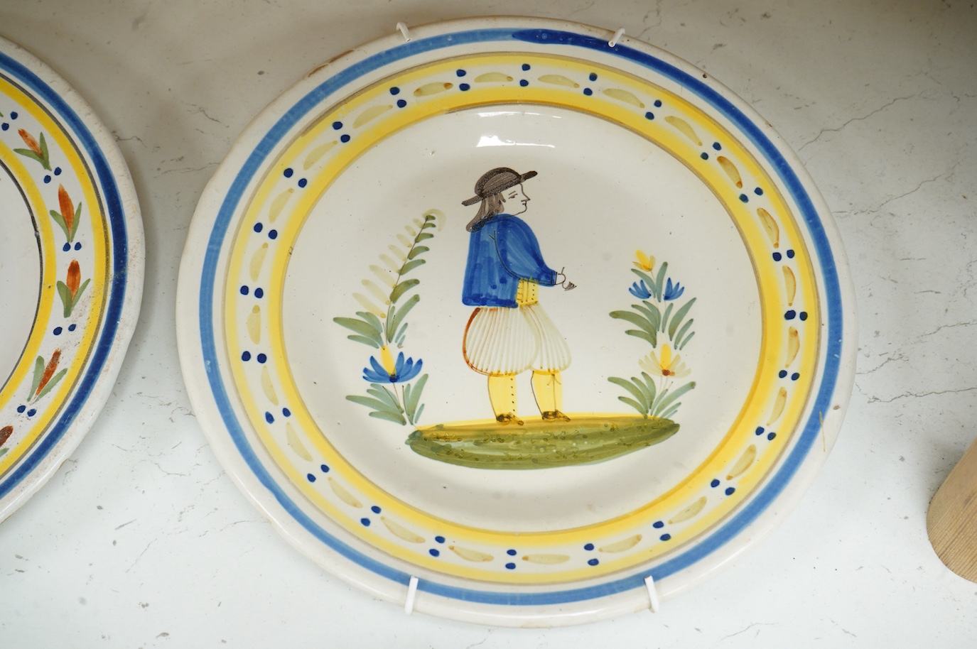 Four Quimper faience plates, each signed to the bases, 23cm in diameter